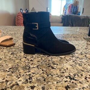 black ankle boot with a block heel and a gold buckle detail